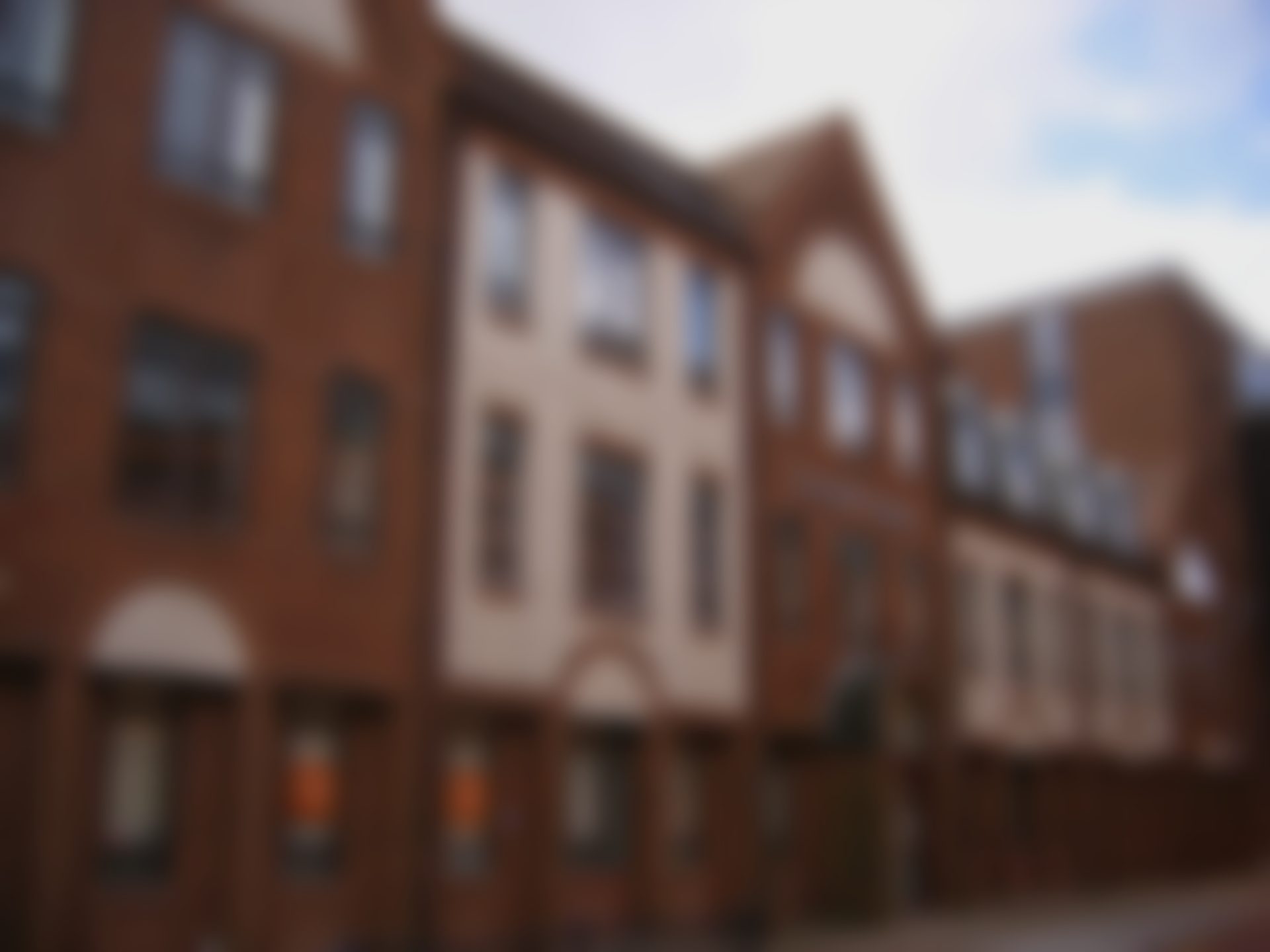 A red-brick UK council house building, softly blurred